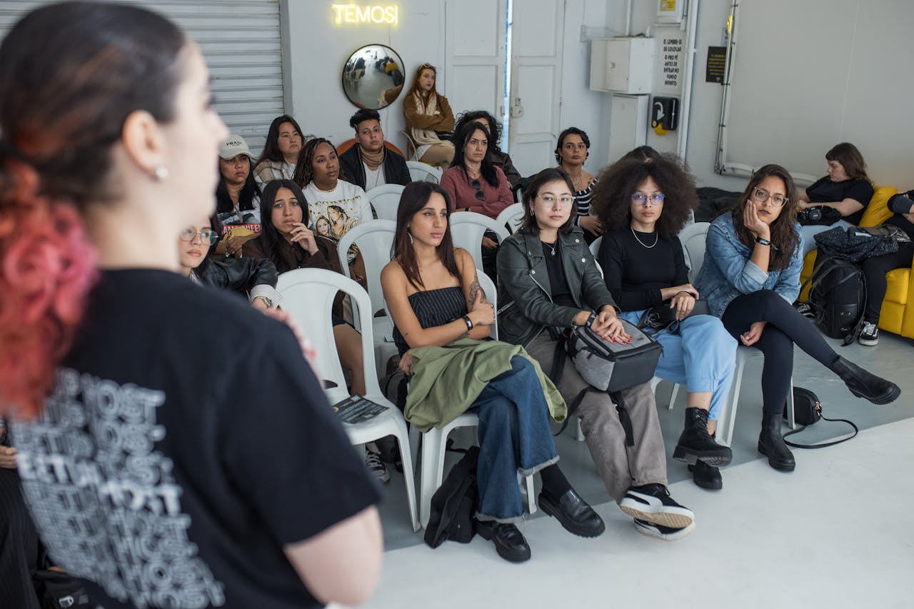 A group of adults attentively listens to a speaker at an indoor workshop.